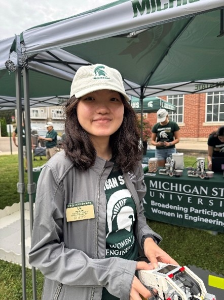 A woman holds a device at an outdoor tabling event