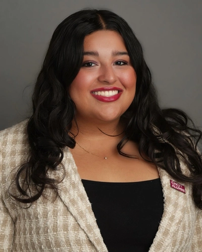 Michigan State University student and Voyager Scholarship recipient Anabelle Sanchez smiling in a plaid white and tan blazer, wearing a red CHCI ALUMNI pin