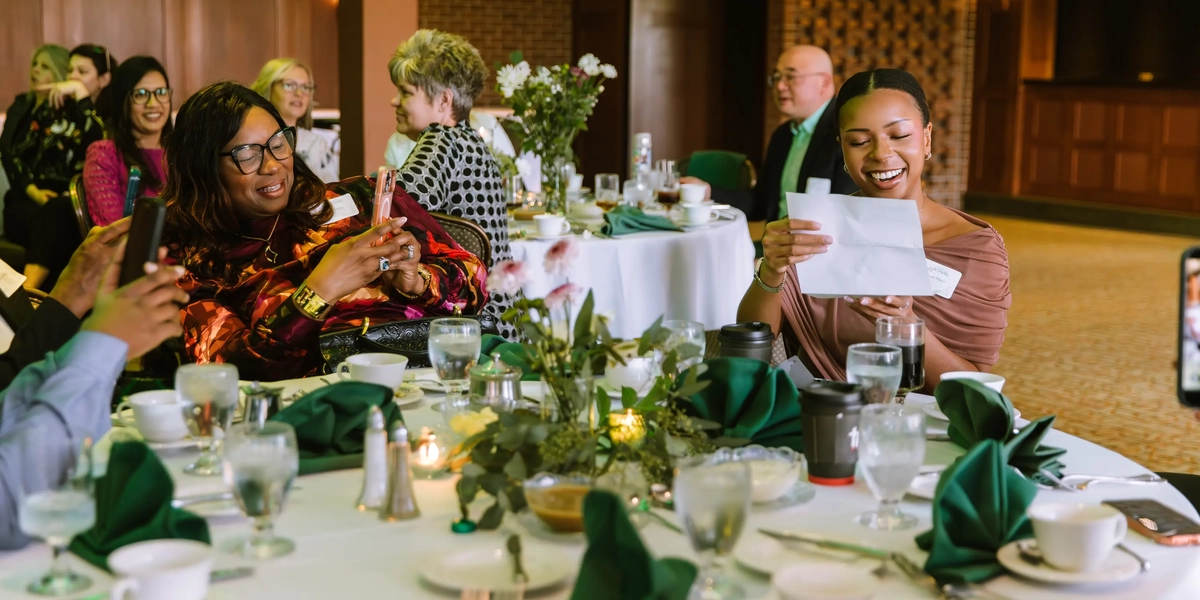 A female student laughing while reading her Match Day letter at a banquet table.