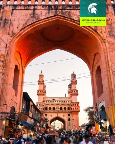 busy street with a view of a building with four spires during golden hour in Hyderabad, India