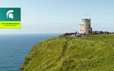 The Cliffs of Mohr, lush green grasses and a tower with people surrounding it