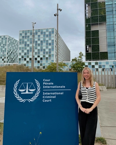Ashlin Stover poses in front of a sign that reads International Criminal Court