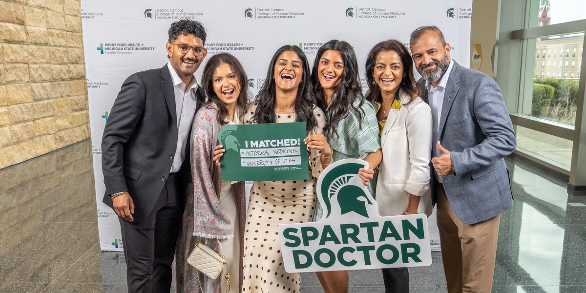 A group of six people posing with "Spartan Doctor" and residency match signs in Detroit.