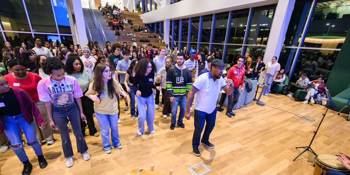 People follow a singer holding a mic while line dancing