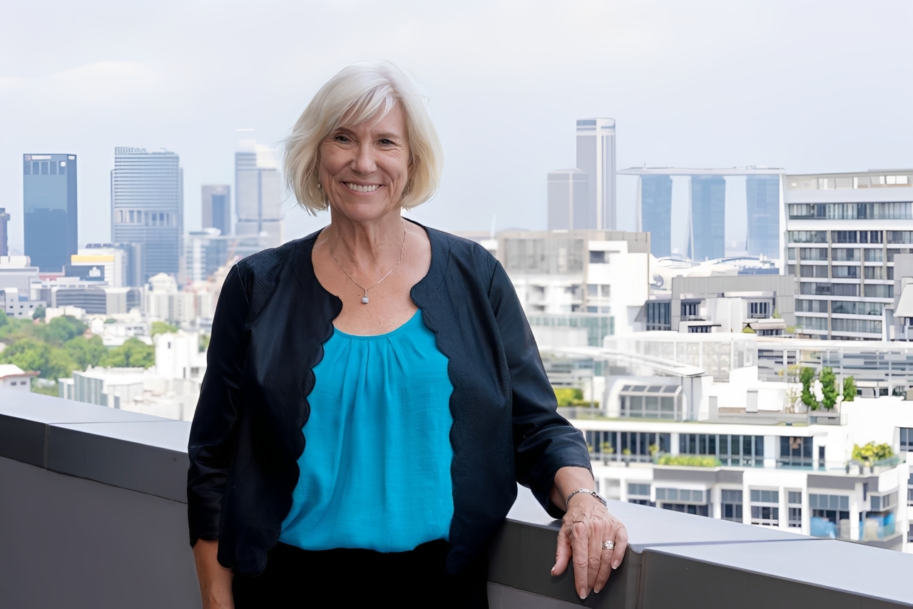 Woman stands outside with a skyline in the background.