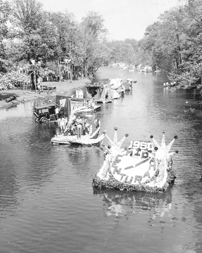 Multiple decorated floats during the 1950 Water Carnival float down the Red Cedar in single file order.