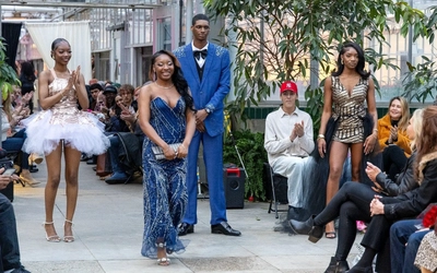 Angel Ennis standing on the runway as the crowd claps next to models wearing her designs.
