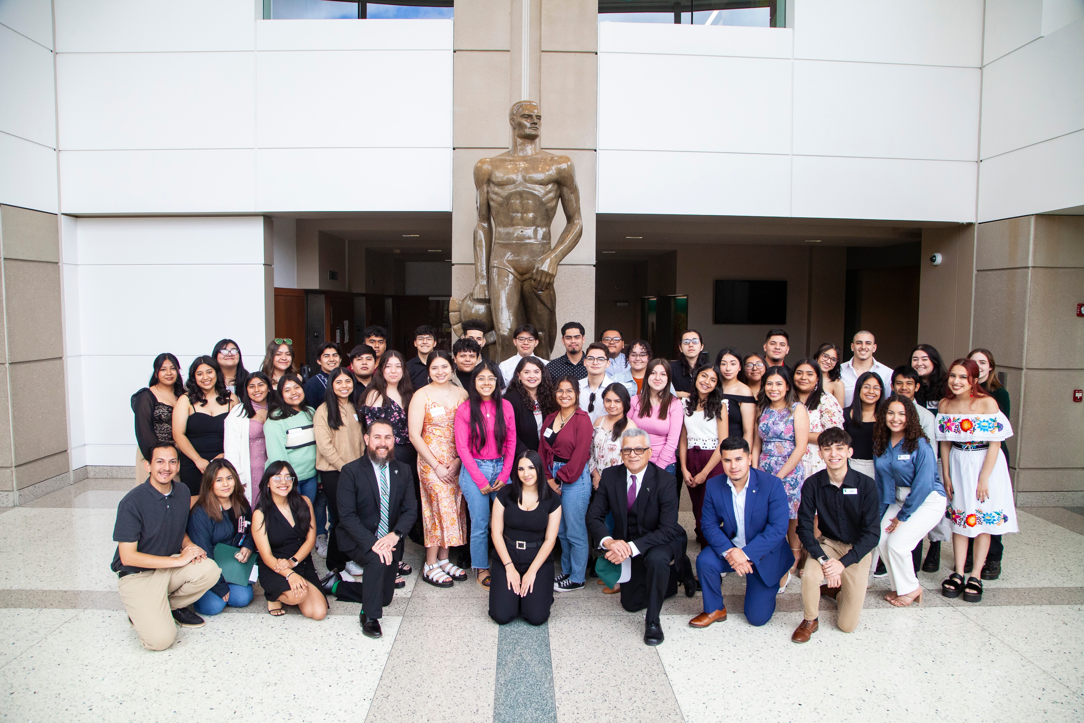 large group of students and staff around a statue