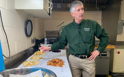 Man standing in room sampling a variety of potato chips.