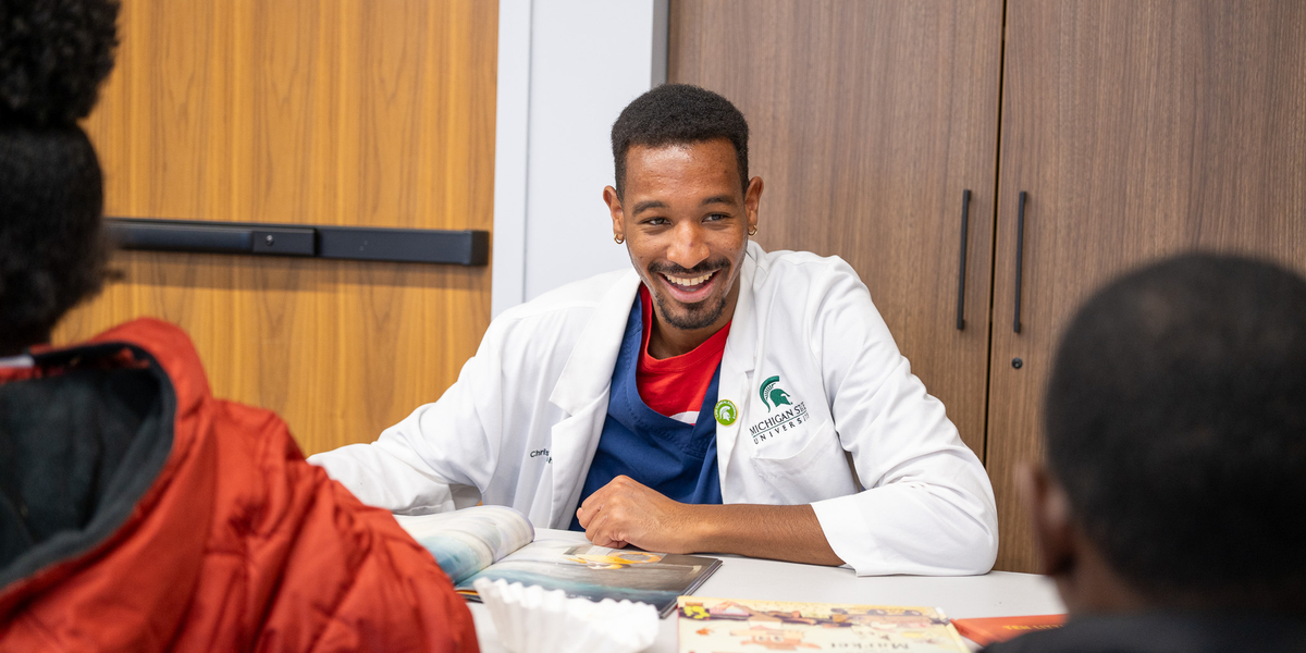 Christopher, an MSU College of Human Medicine student, reads with youth at Gloria Coles Flint Public Library. The Flint Registry served as an elective for third-year medical students to offer first-hand experience in community driven public health. Photo by Josh Kennedy