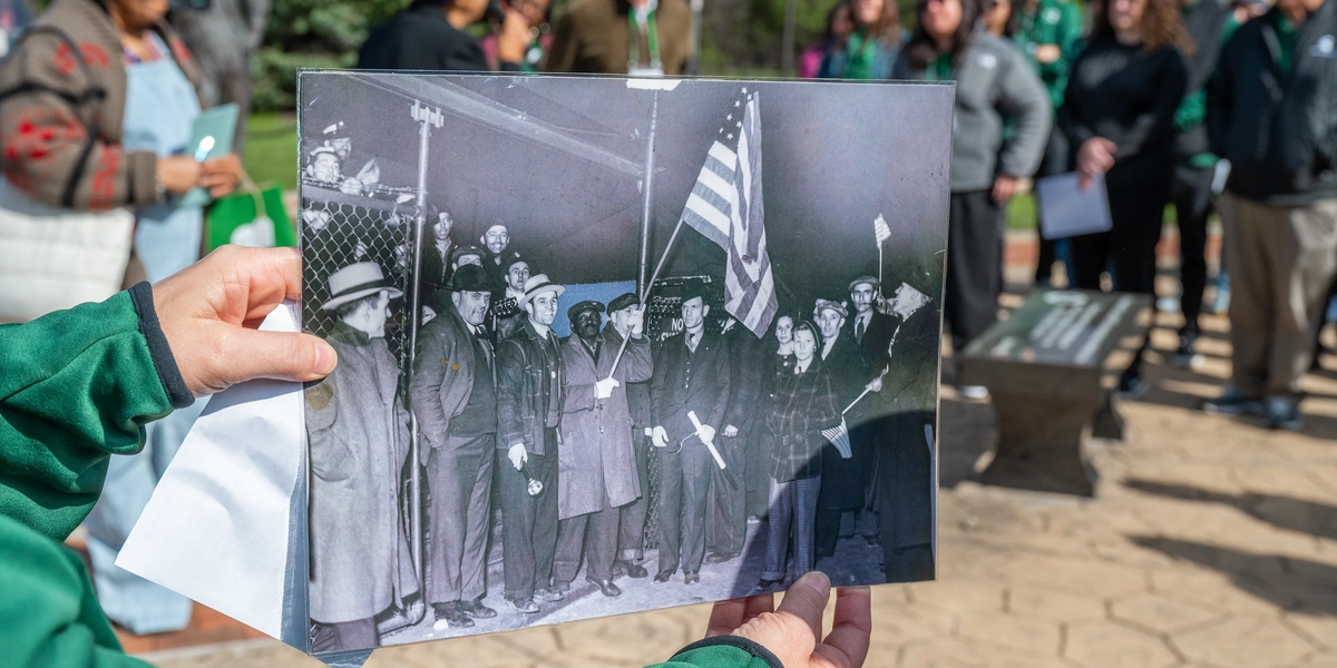 A person holds a black and white photo that shows hows the successful end to the autoworkers’ strike in Flint.