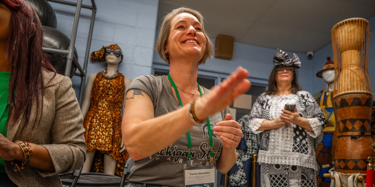 A person smiles and is about to push their hand down to a drum