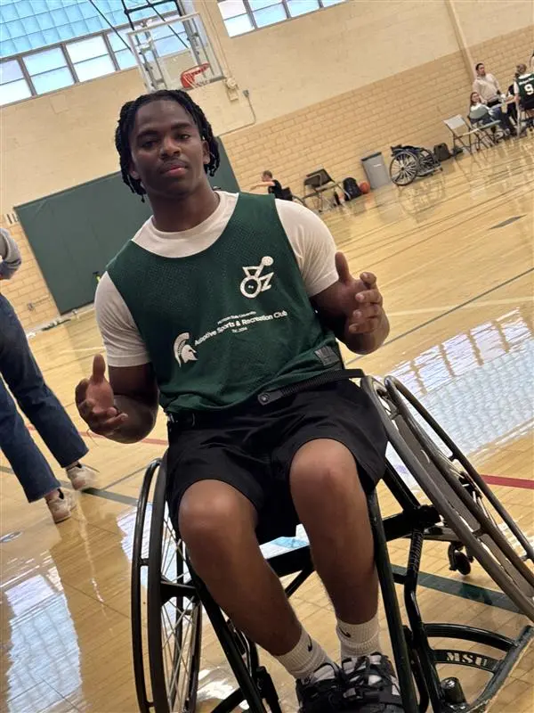 A man sits in an adaptive wheelchair on a basketball court