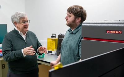 Two researchers have a conversation inside of a research laboratory.