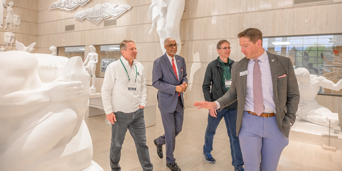 A group of people walk through the Marshall M. Fredericks Sculpture Museum