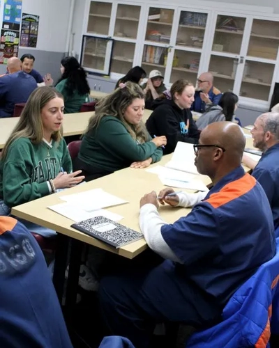 MSU undergraduate students sit at a table and discuss with incarcerated students.