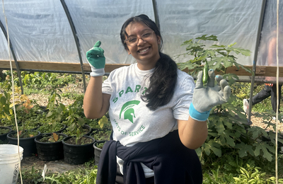 Michigan State University student, Senior Maitreya Wankhede, poses inside a greenhouse.