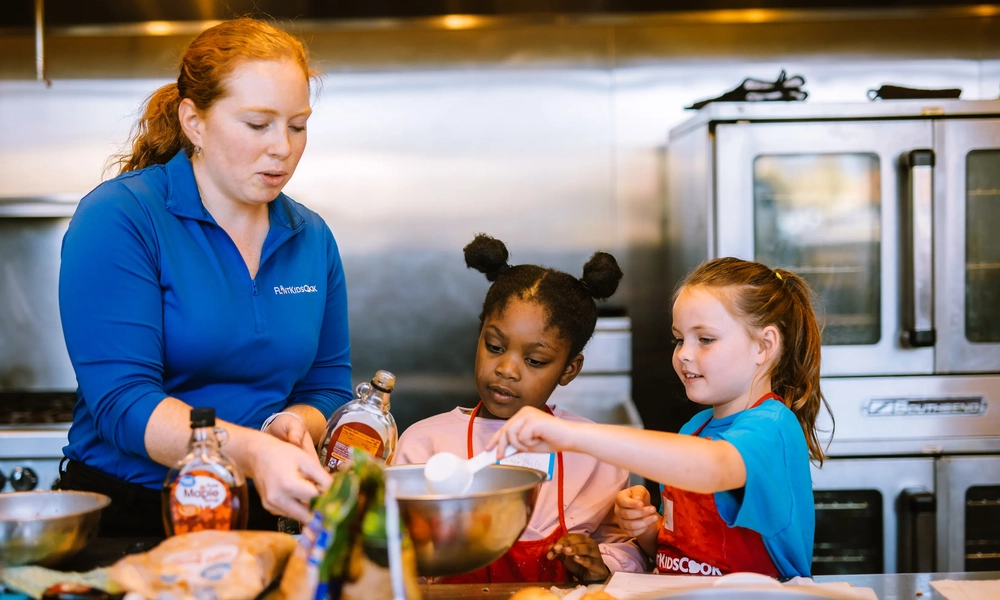 Flint Kids Cook, Michigan’s first fruit and vegetable prescription program for kids, increases access to healthy, locally grown foods by providing children with prescriptions for fresh fruits and vegetables when they visit the pediatrician. Here, 
Flint Kids Cook participants make a new recipe at the Flint Farmers’ Market test kitchen alongside Sarah Egan, project coordinator for the cooking programs. Photo courtesy of the MSU Charles Stewart Mott Department of Public Health.
