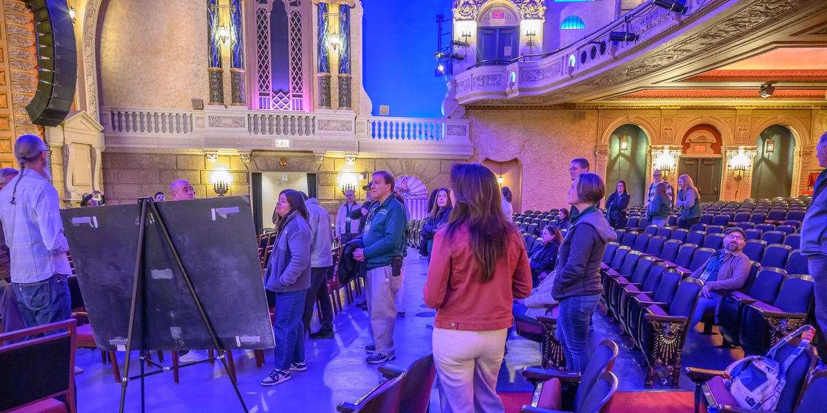 A group of people mill about in the seating area of a theater