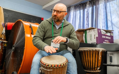 Man in glasses plays a Kuungana African Drum.