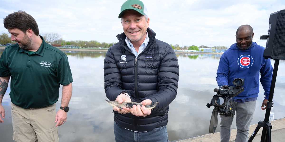 President Kevin M. Guskiewicz holds a lake sturgeon