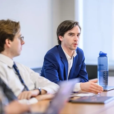 Will Castanier speaking at a table during the 2025 JMC Research Showcase.