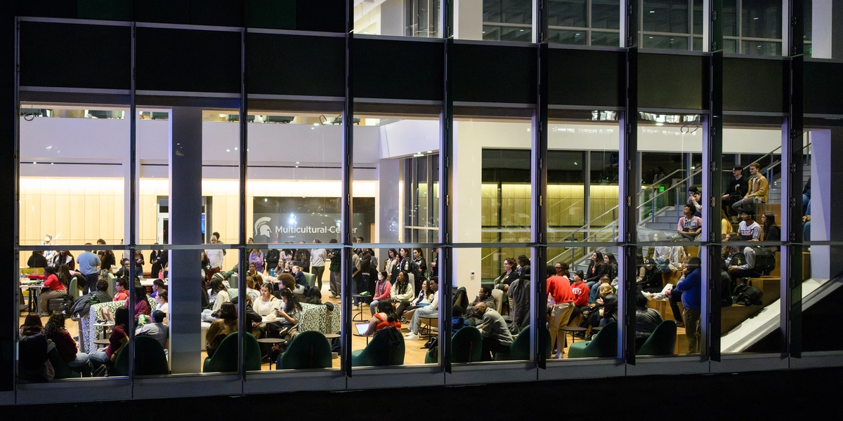 people gather inside a building seen through glass panel windows