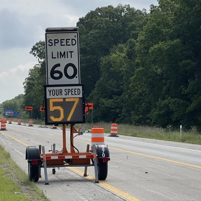 An image of a highway with a digital speed detector placed under the speed limit sign.
