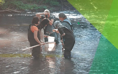 Group taking a picture of something in a net in a river