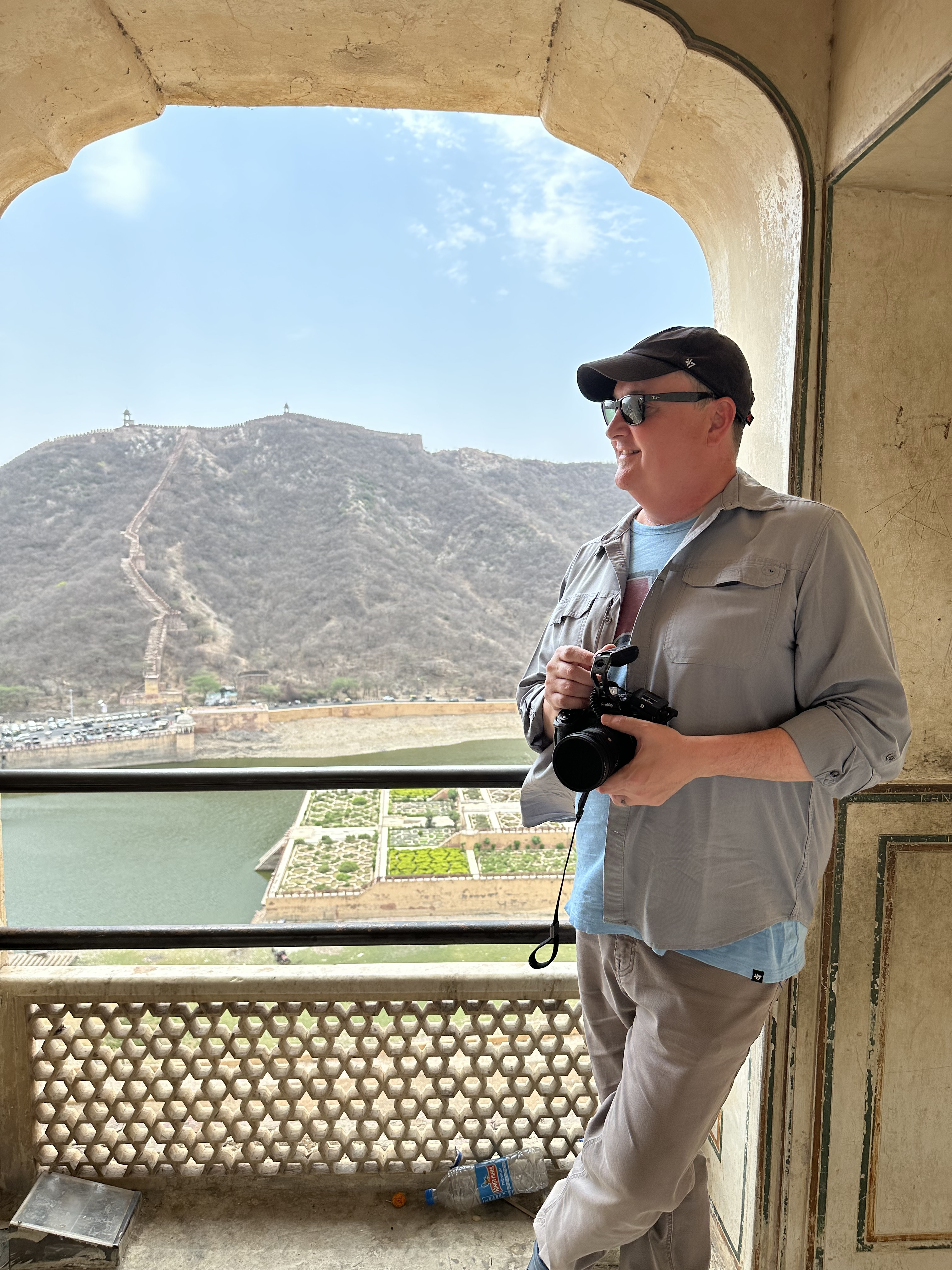 a man stands holding a camera with a scenic view