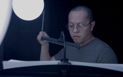 An image of Austin Oting working at a desk lit by a bright lamp.