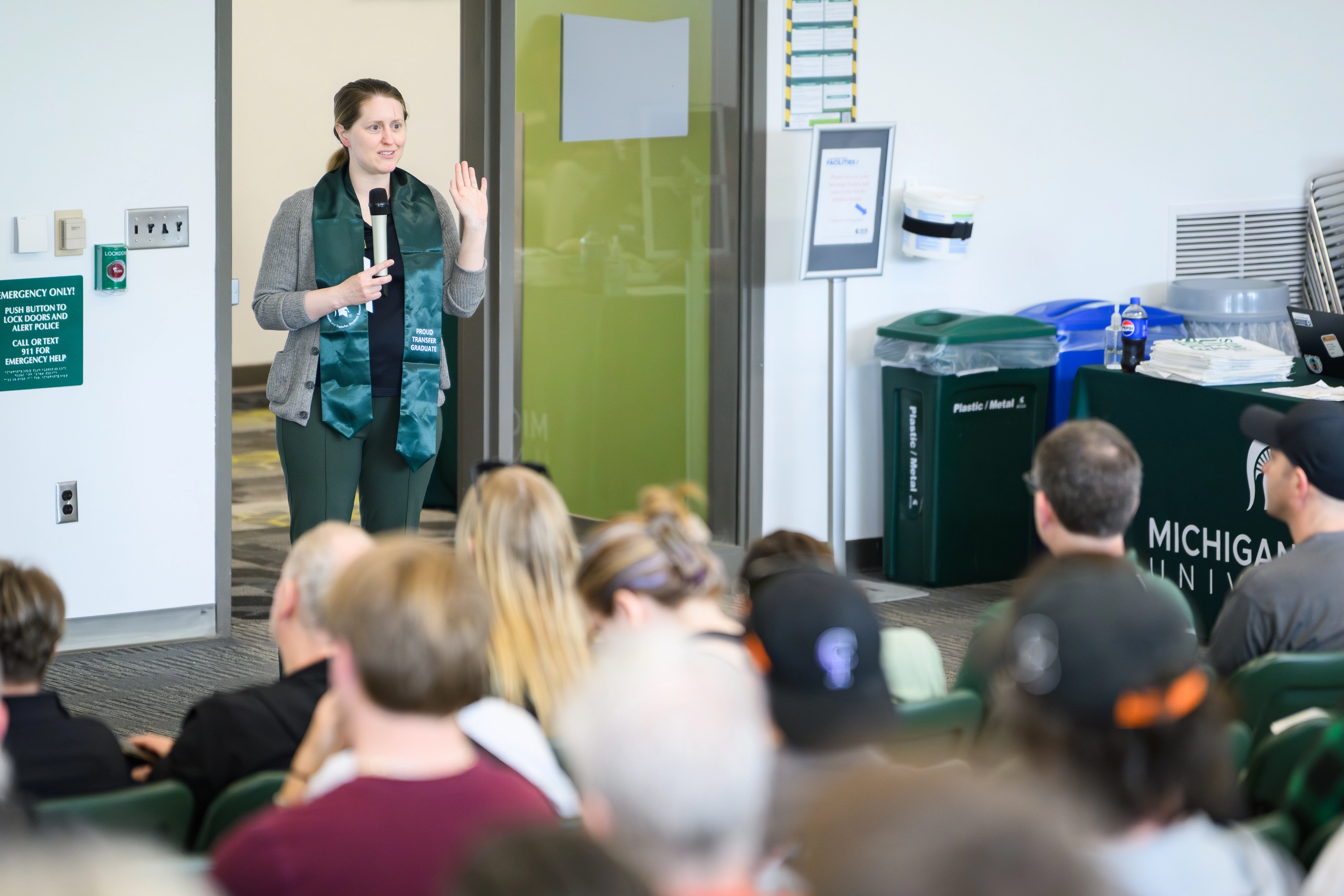 A woman speaks into a microphone in front of students