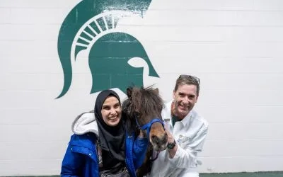 Mona and Dr. Komáromy crouched on either side of seeing eye horse Cali.