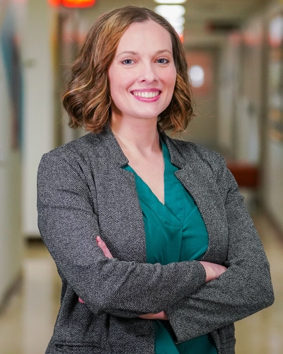 Professional portrait of a woman in a grey blazer and teal shirt.