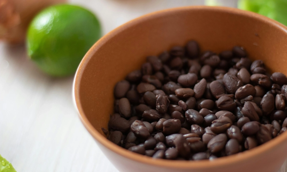 Image of a bowl of black beans next to a lime
