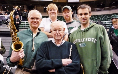 Henry Nelson, center, with his son Jack holding a saxophone and other members of the family surrounding him inside a stadium.