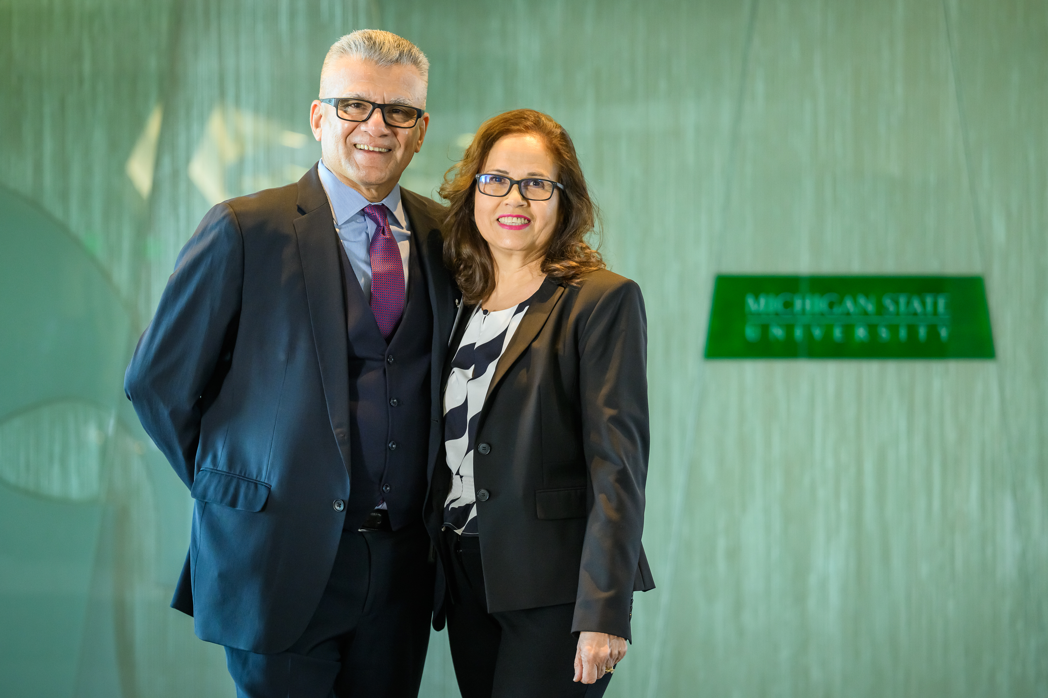 a man and a woman in business clothes pose for a photo