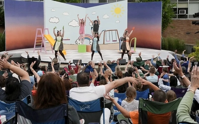 An image shot of performers on a stage behind a crowd following the performers' actions.