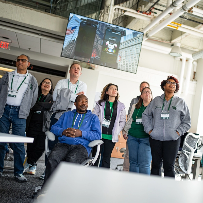 An Apple Developer Academy student presents her app, Roami, to a small group at a standing desk.