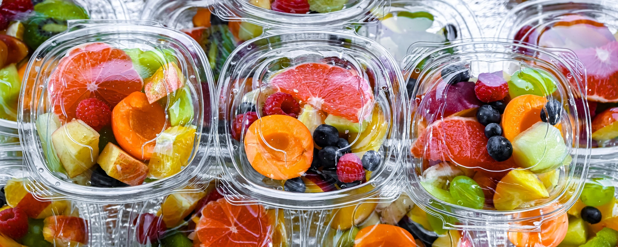 Clear plastic containers filled with colorful mixed fruit pieces.