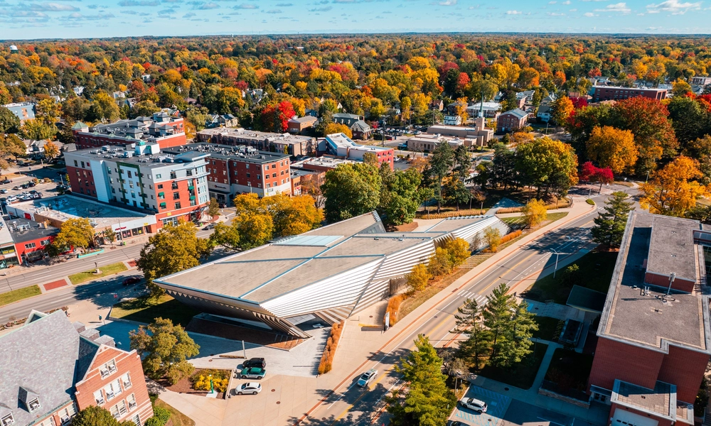 An aerial view of the Broad Art Museum and its striking angles on a sunny fall day with lush red and yellow trees in the background