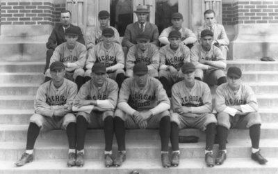 Black and white photo of the 1925 Michigan State Baseball team. Players posed in their uniforms in three rows and catcher's gear in front of them. In the far right on the second row is Perry Fremont, who may have created the nickname the Spartans for MSU