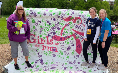Pfeiffer, Karly Bender, M.S., Cailyn VanCamp, Ph.D. pose at the MSU Rock during a Girls on the Run International event