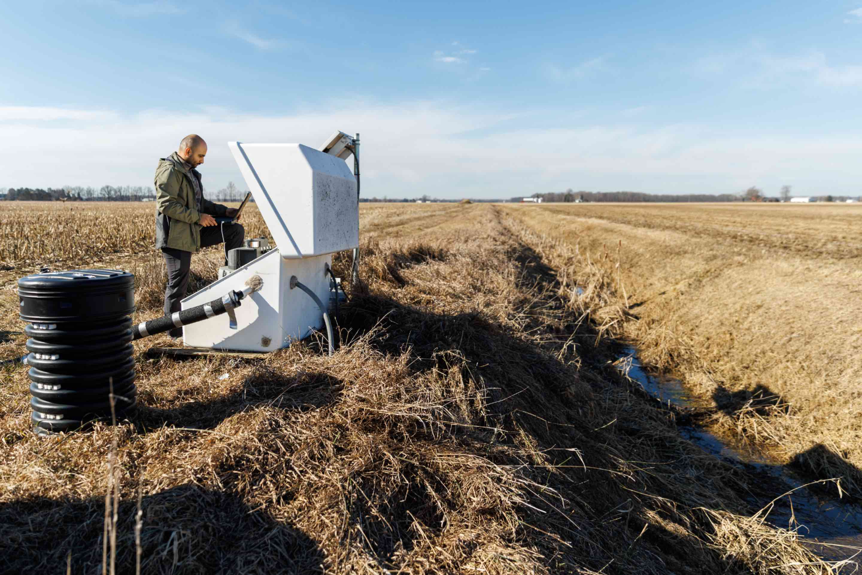 Jim and Laurie Isley, dedicated stewards of Sunrise Farms in Palmyra, Michigan, standing proudly in front of their farm's equipment and infrastructure, showcasing the real-world application of sustainable agricultural practices.