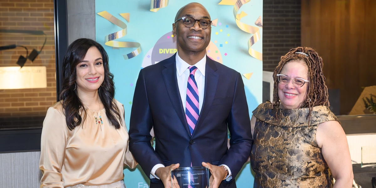 Three people pose for an award photo