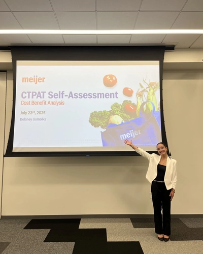 Delaney Gomolka stands in front of projector screen.