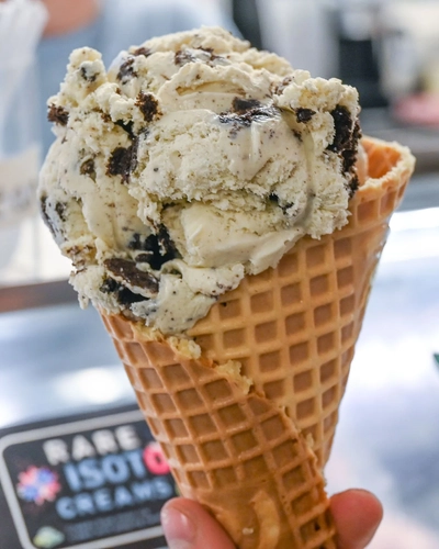 A handheld ice cream cone against the backdrop of the MSU Dairy Store counter.