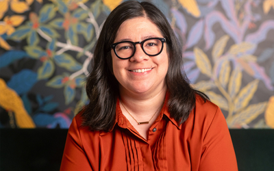 Alejandra Marquez posing in front of a wall with a bright botanical design