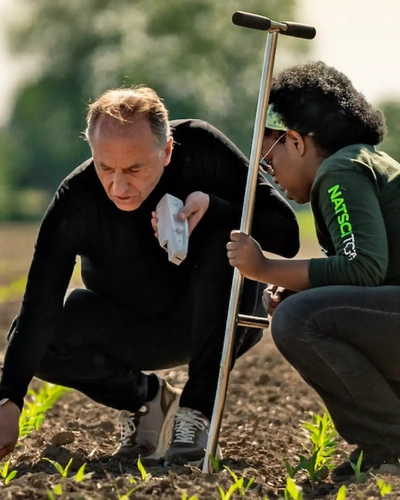 Bruno Basso and student inspecting crop seedlings in a field.