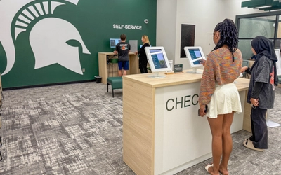 Students standing at kiosks selecting resources at Spartan One-Stop.